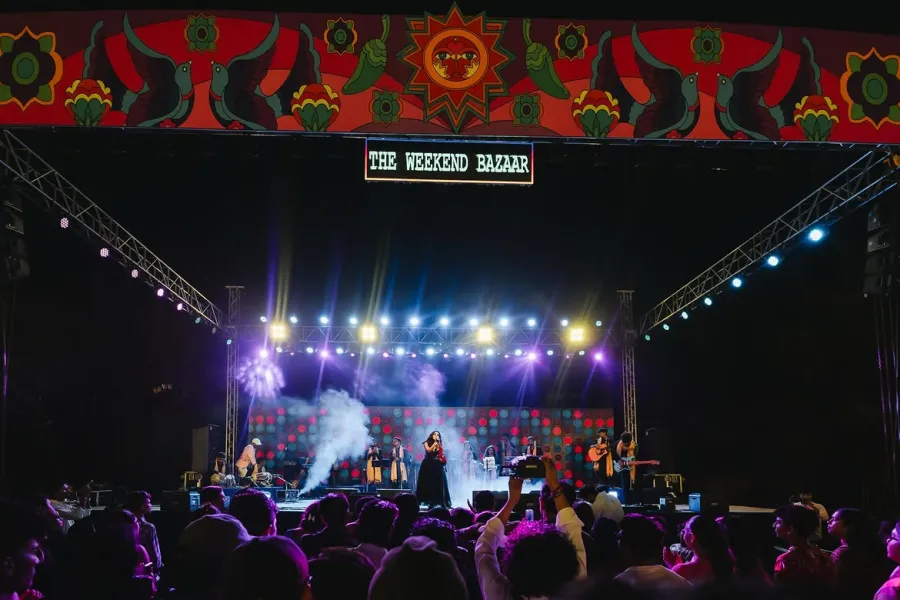 A band performing on the lit Weekend Bazaar stage at night