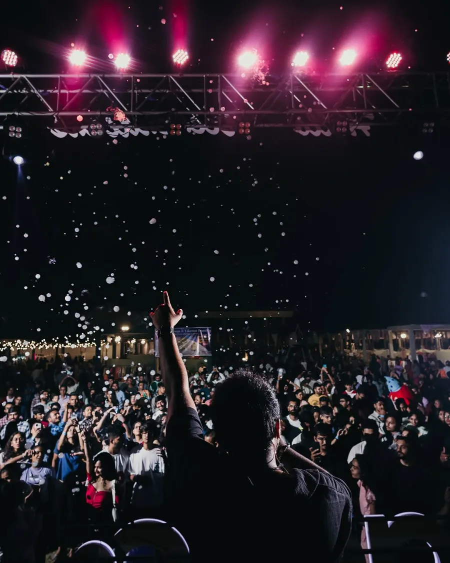 A performer facing the crowd under pink stage lights, confetti in the air