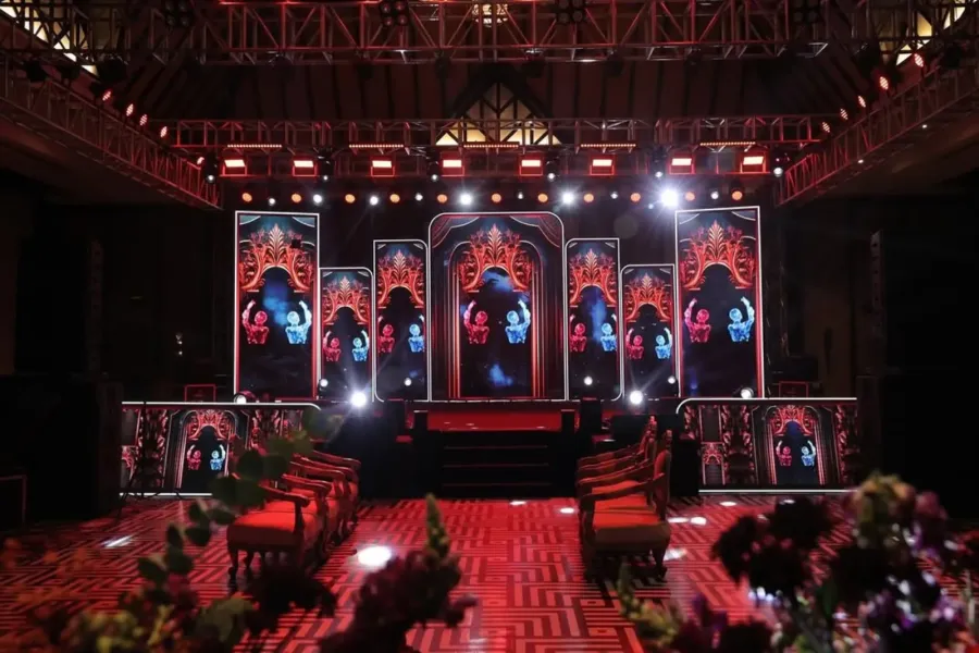Indoor hall with arched, lit backdrops and rows of seating