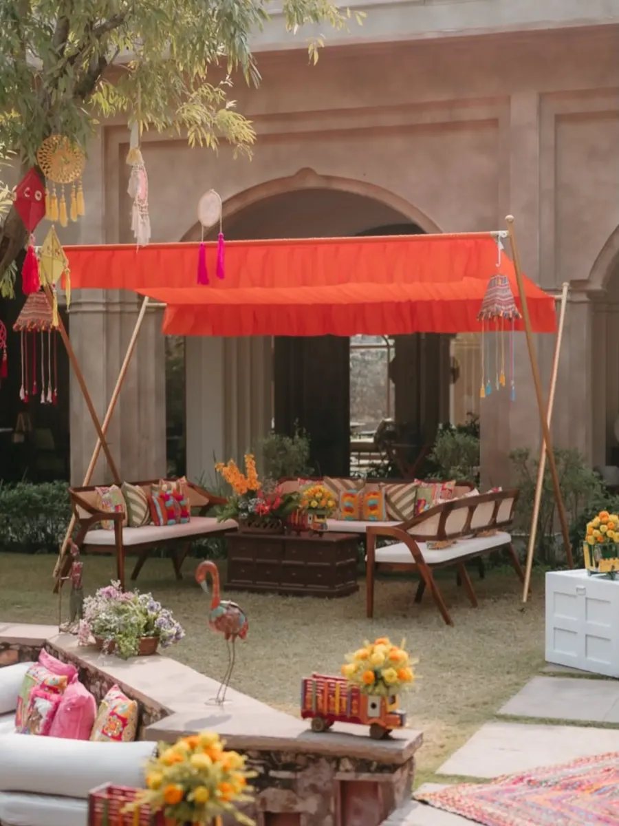 Heritage courtyard lounge under a saffron awning, layered with rugs and cushions