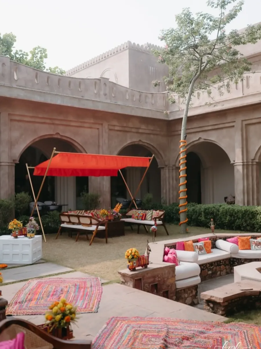 Courtyard seating with red awnings against carved stone arches