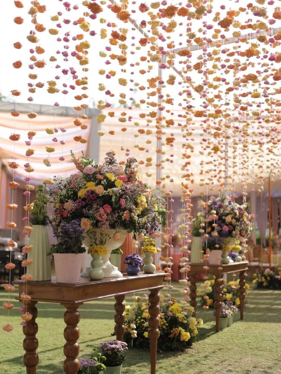 Hanging floral strands above a table of flower urns in a garden