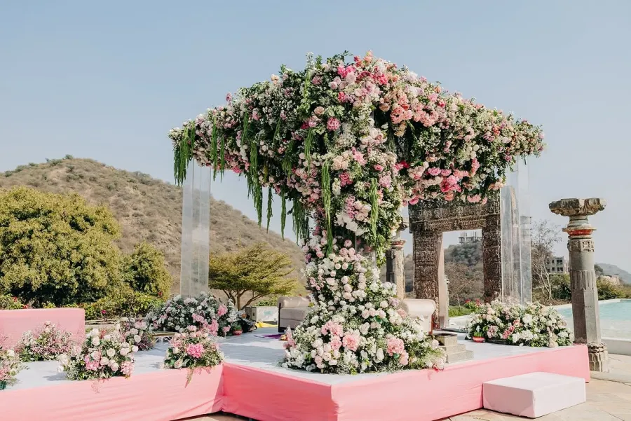 Floral arch mandap on a pink stage with hills behind