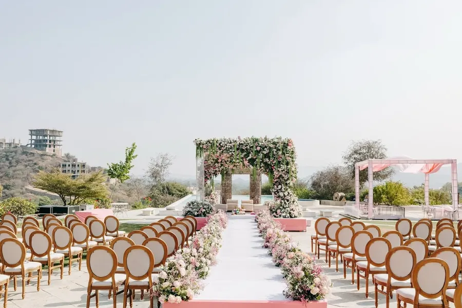 Long ceremony aisle flanked by gold chairs and a floral arch
