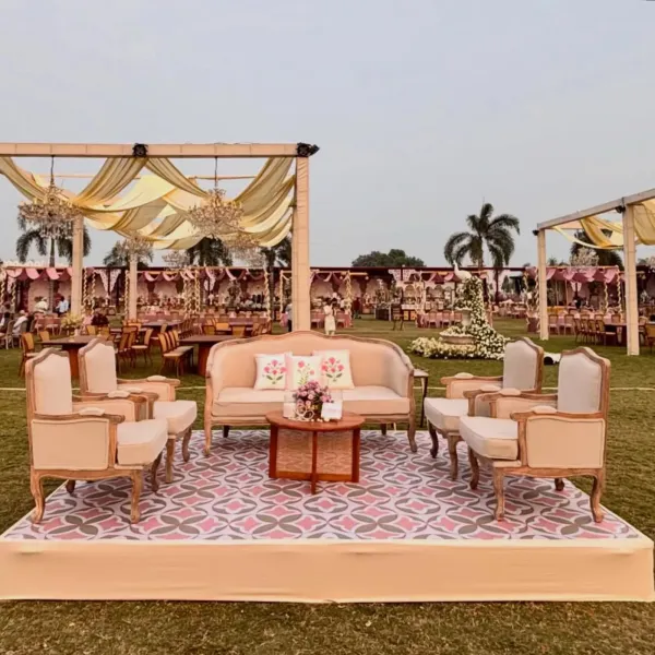 Open-lawn lounge seating on a printed platform, draped canopy above, at dusk